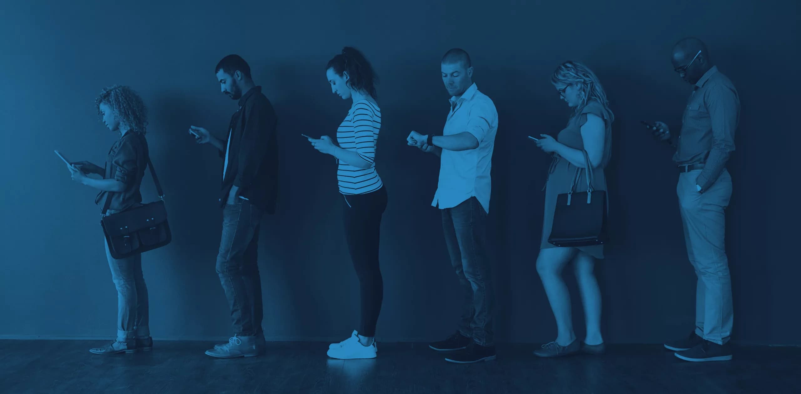 Des personnes font la queue en regardant leur téléphone.